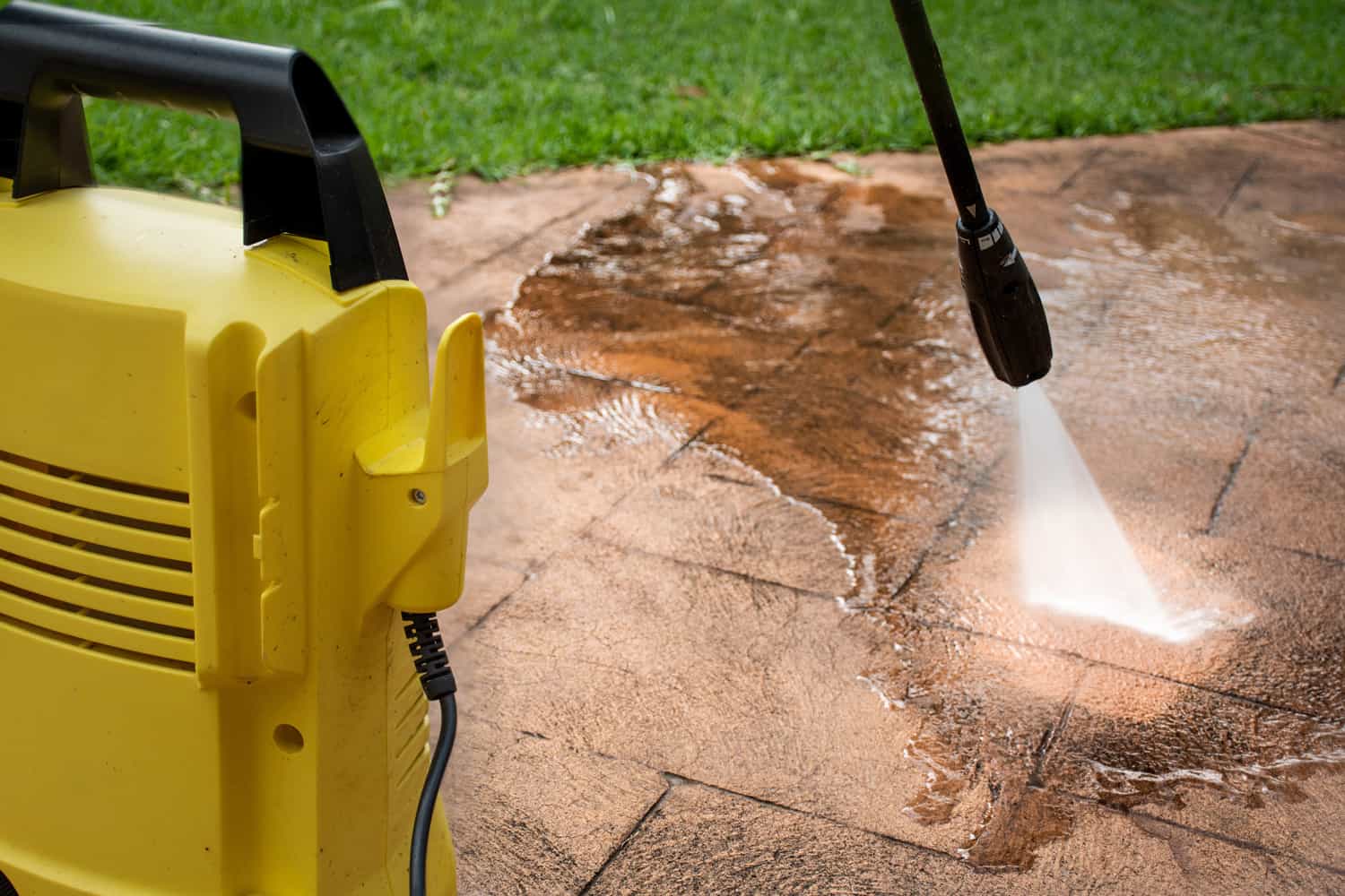 Cleaning backyard paving tiles with pressure washer. Spring clean up