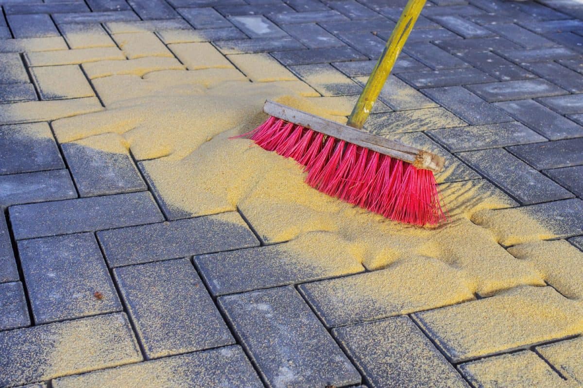 Sweeping in joint sand on a construction site

